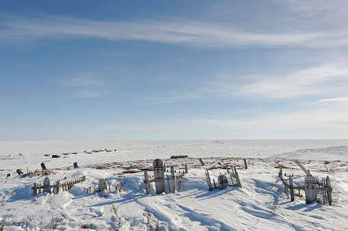 Old grave yard overlooking Shingle Point, Canada's Yukon Territory Beaufort Sea coast in late Winter with arctic ocean and whaling camp background