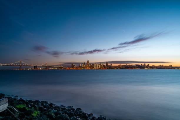 piękna scena wieczornej panoramy san francisco i mostu bay bridge z błękitnym niebem zachód słońca, kalifornia, usa - sun lighting equipment san francisco county downtown district zdjęcia i obrazy z banku zdjęć