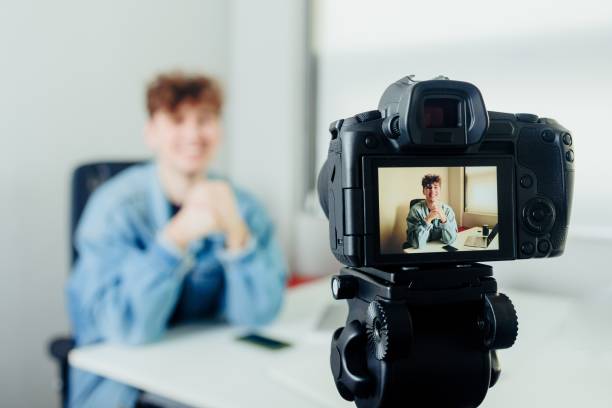 Young handsome blogger with a camera filming himself in a room