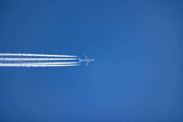 istock Plane and its white trail in the clear blue sky 1455196855