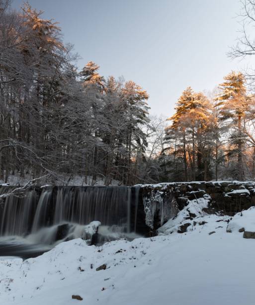 istock Waterfall flowing over the rocks in the forest in winter 1455197150