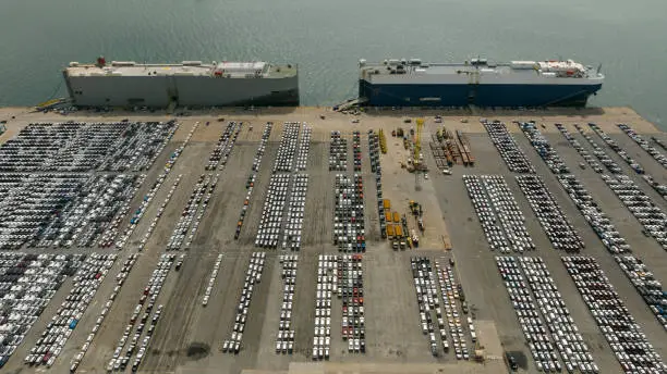 Large RoRo (Roll-on Roll-off) into Commercial dock loading new car product order for sale for export international on the sea, business service transportation concept, aerial view