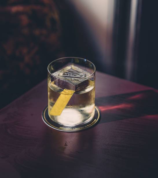 Tasty cocktail with a big ice cube and a lemon zest inside A tasty cocktail with a big ice cube and a lemon zest inside giant cube stock pictures, royalty-free photos & images