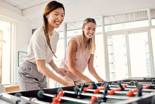 pebolim, mulheres e amigas jogando futebol de mesa em um escritório para diversão, vínculo e competição no trabalho com felicidade, energia e motivação. funcionários desfrutando de jogos de futebol para team building - office business soccer exercising - fotografias e filmes do acervo