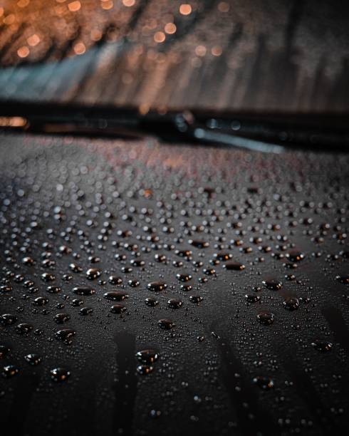 A vertical closeup of waterdrops on a glass surface on a blurred background
