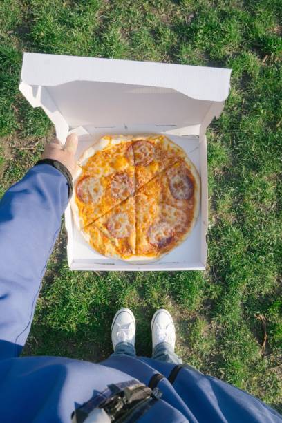 Top view of a person with pizza on green grass background