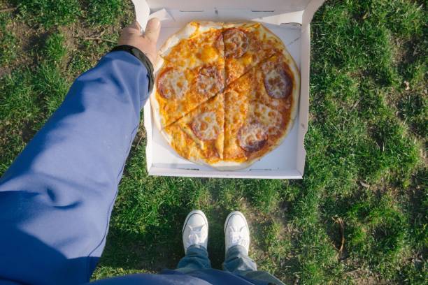 Top view of a person with pizza on green grass background