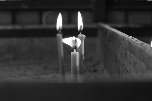 A grayscale shot of burning candles