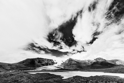 A greyscale shot of crazy clouds above wild landscape
