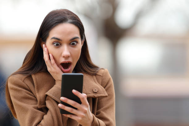 istock Amazed woman in winter checking cell phone 1455199832