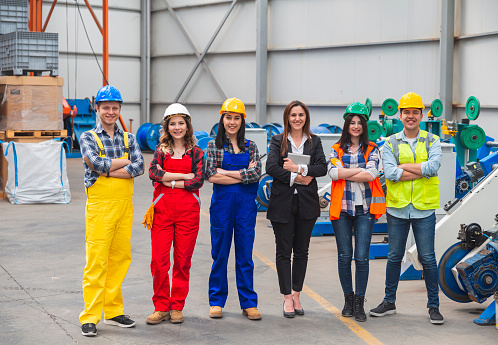 Portrait of distribution warehouse workers team working together and looking at camera in work overalls