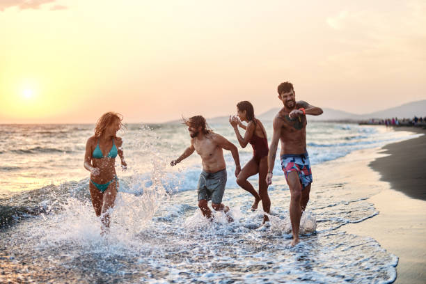 istock Cheerful couples running on the beach at sunset. 1455202331
