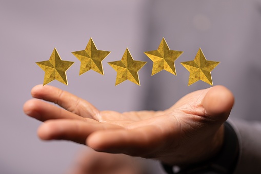 The 3D rendered five-star rating concept over a person's hand on the background