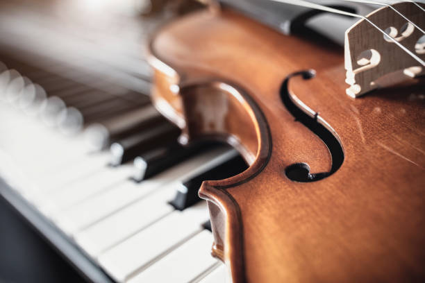 violino em cima de teclas de piano fundo - piano piano key orchestra close up - fotografias e filmes do acervo