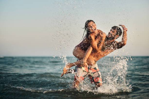 istock Cheerful couple having fun while splashing and piggybacking at sea. 1455203399