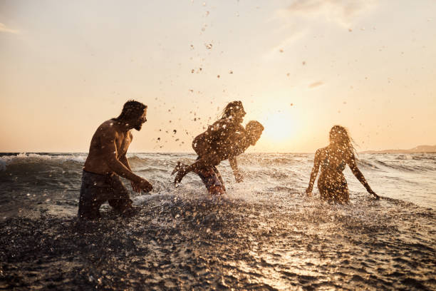 istock Carefree friends having fun while playing in sea at sunset. 1455203704