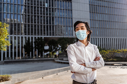 Asian businessman wearing a mask looking seriously
