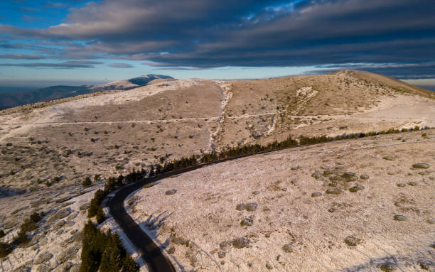 montañas cubiertas de nieve al atardecer con un camino sinuoso en primer plano vista aérea - road winding road mountain spiral staircase fotografías e imágenes de stock