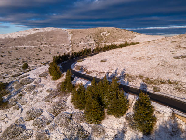 montañas cubiertas de nieve al atardecer con un camino sinuoso en primer plano vista aérea - road winding road mountain spiral staircase fotografías e imágenes de stock