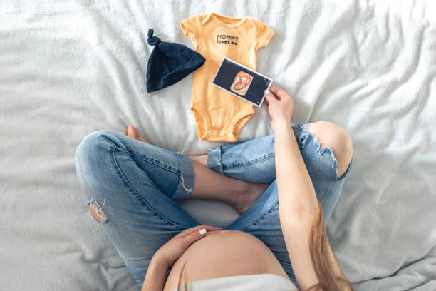 schwangere frau, ultraschallbild und babykram, eine mutter erwartet ein baby. - human pregnancy telephone ultrasound family stock-fotos und bilder