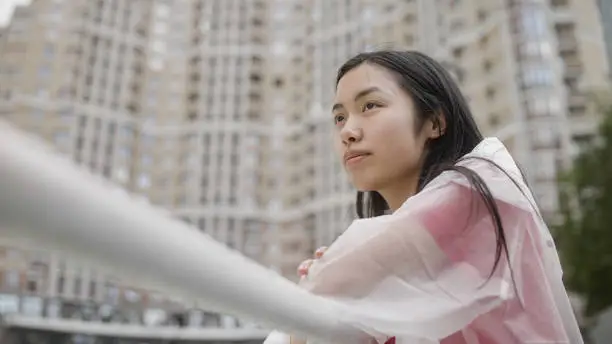 Beautiful asian woman leaning on bridge handrails, enjoying view of cityscape