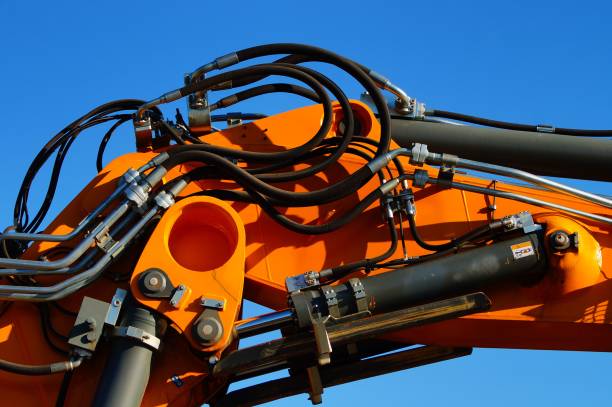 Detail of the hydraulic system of a heavy construction machine Detail of the hydraulic system of a heavy construction machine. Cylinders and pipes in the blue sky. Beautiful play of colours. hydraulics stock pictures, royalty-free photos & images