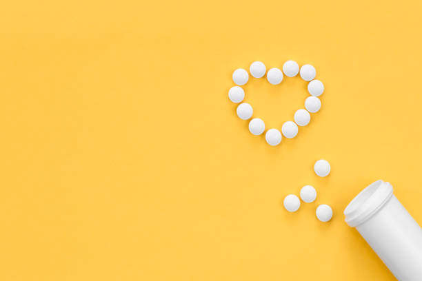 istock Scattered heart shaped pills on yellow background, flat lay. 1455207378