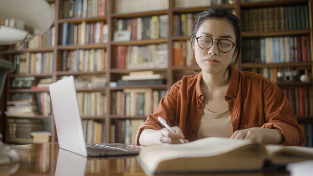 istock Beautiful Vietnamese woman student spending time in university library with laptop and notebooks 1455207436