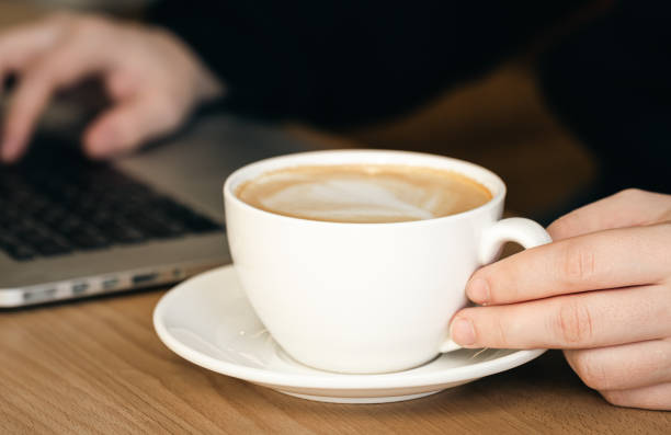 istock Close-up, a cup of coffee and on a blurred background with a laptop. 1455208091