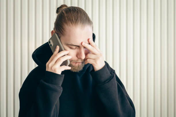 istock A young man talking on smartphone and holding his head, concept of problem. 1455208098