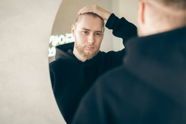 istock An attractive young man with a beard looks at himself in the mirror. 1455208106
