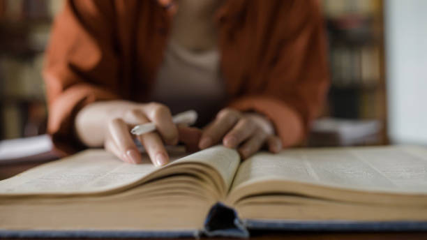 istock Female writer reading encyclopedia, doing research before writing an article 1455208789
