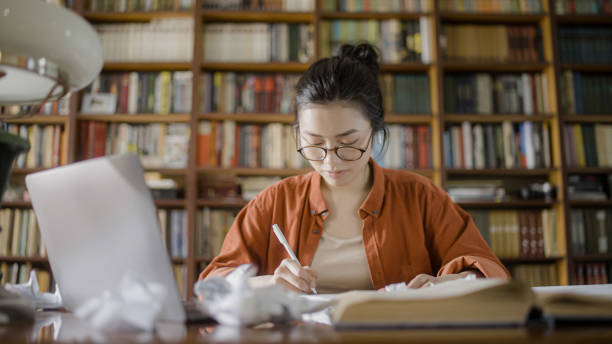 istock Young asian woman in the middle of creative process, brainstorming ideas for an article 1455208931
