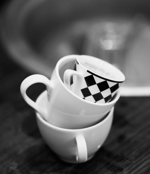 istock Grayscale shallow focus of white marble cups and a white and black checked cup, blurred background 1455209583
