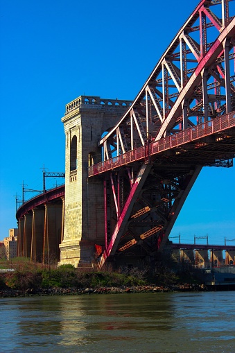 A vertical shot of the Hellgate Bridge over the river under the blue clear sky in Astoria Park