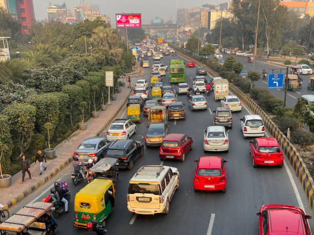 istock Image of traffic jam on motorway viewed from overpass, motorbikes with pillion passengers, buses, cars, auto rickshaws stationary on highway, main road with striped barrier, focus on foreground 1455210296