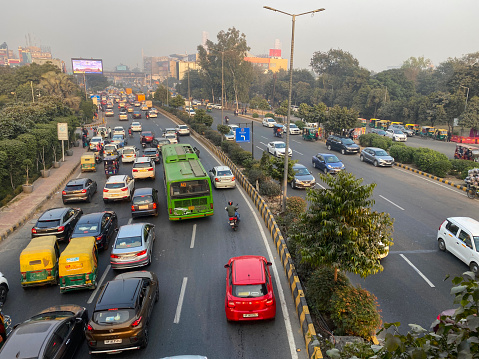 Stock photo showing view from overpass of traffic with motorcycles, cars and auto rickshaws seen gridlocked in a traffic jam running bumper to bumper on multilane highway.