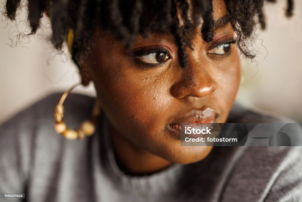 Young woman looking away, contemplating her New Year's resolutions Portrait of happy young Black woman looking away, smiling while contemplating her New Year's resolutions. Part of a series. Women Stock Photo