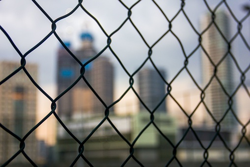 A blurry shot of tall buildings through the fences