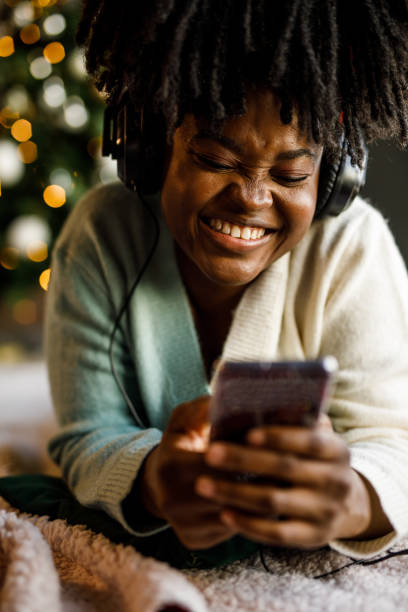 jeune femme allongée sur le sol, près du sapin de noël, écoutant de la musique au casque - tree house audio photos et images de collection