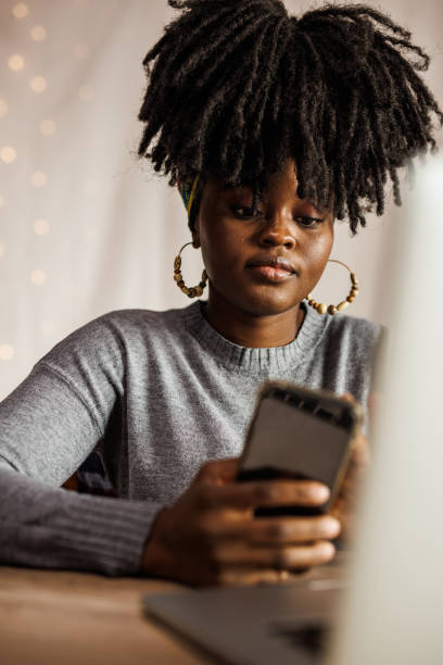 istock Young woman checking text messages on smart phone while working at her desk 1455215014