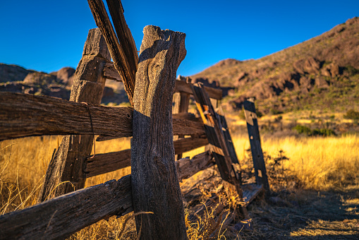 Organ Mountains, Desert Peaks National Monument in Las Cruces, Doña Ana County, New Mexico, Southwestern USA, rustic weathered wooden ranch fence over the golden grasses in the meadow at Dripping Springs Natural Area.