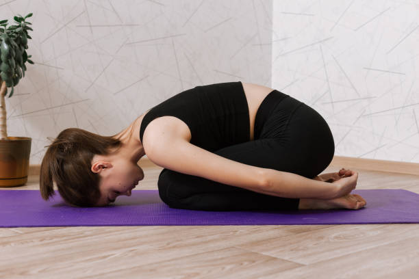 istock Calm female lying on exercise mat and doing yoga in apartment 1455224003