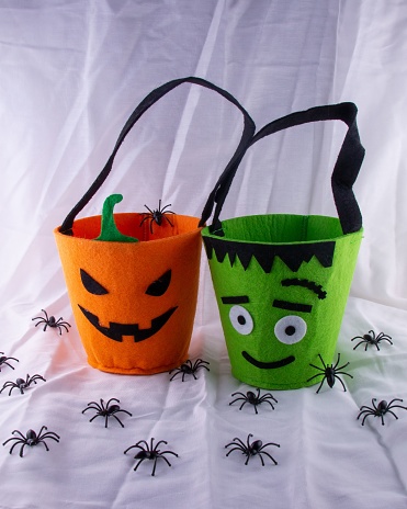 A vertical shot of orange pumpkin and green monster candy bags with spiders