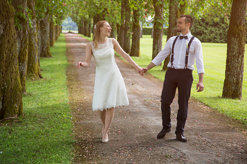 Young couple in wedding dress walking in nature forest path. Having fun. Very happy.