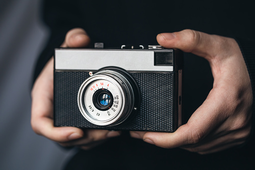 Close-up, retro film camera in male hands, on a blurred background.