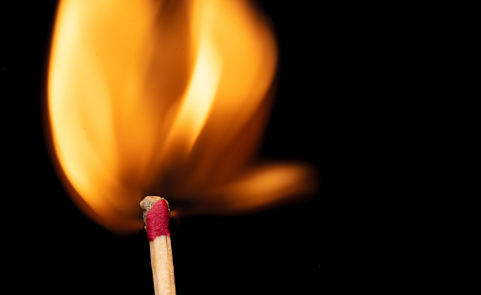 Close-up of igniting matchstick against coloured background.