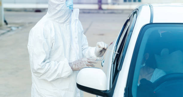istock Medical worker in protective suit screening woman Driver to Sampling secretion to check for Covid-19. 1455229616