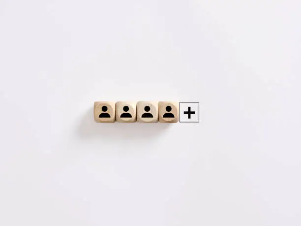 Photo of Creating a successful team. Vacant job position. Search for new employees. Hiring, staffing and employment. Personnel management. Leadership position. Wooden cubes with employee symbols and plus sign.