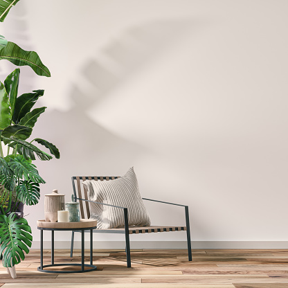 Empty cozy retro interior with a chair in front of a  white wall background on the hardwood floor with copy space and decoration (lush foliage: monstera, banana/palm tree, pillow). A low coffee table with ceramic containers and candles. 70 - 80s decoration style. A slight vintage effect was added. 3D rendered image.